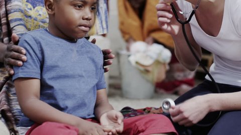 A medical worker from a charity organization chats with the mother of a young boy she has been examining. In slow motion.