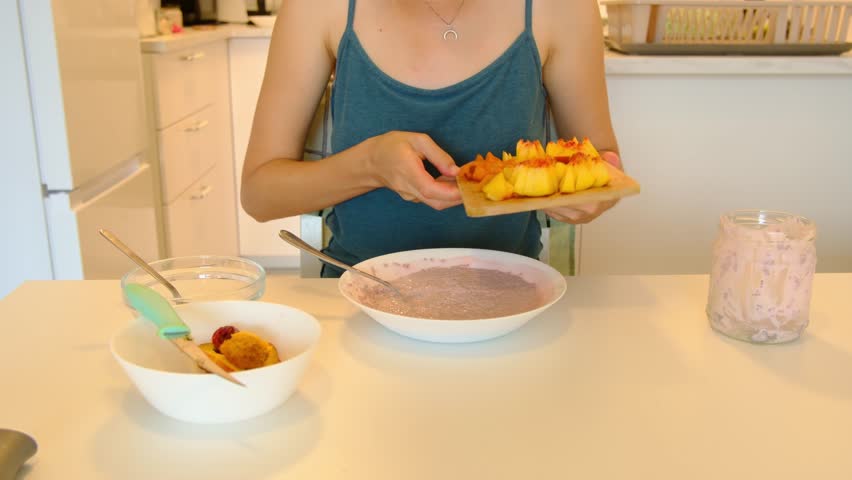 Young woman prepare tasty chia seed pudding with peaches and apricots at table, healthy eating habits