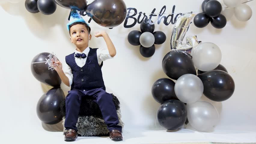 Happy Child Wearing Birthday Hat and playing with balloons at Indoor Birthday Celebration