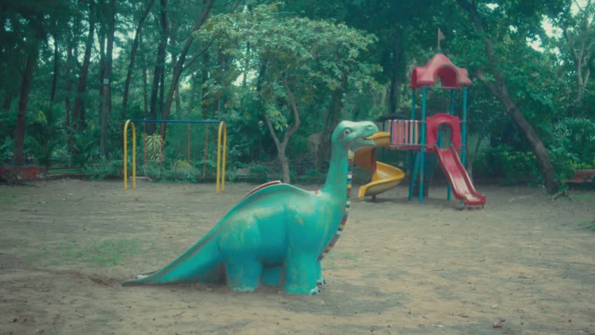 Colorful dinosaur playground equipment in a quiet park surrounded by trees, creating a cheerful outdoor recreation scene for family, childhood, and leisure themes.