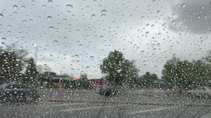 Stormy weather seen through a car window with raindrops falling and blurring the view outside