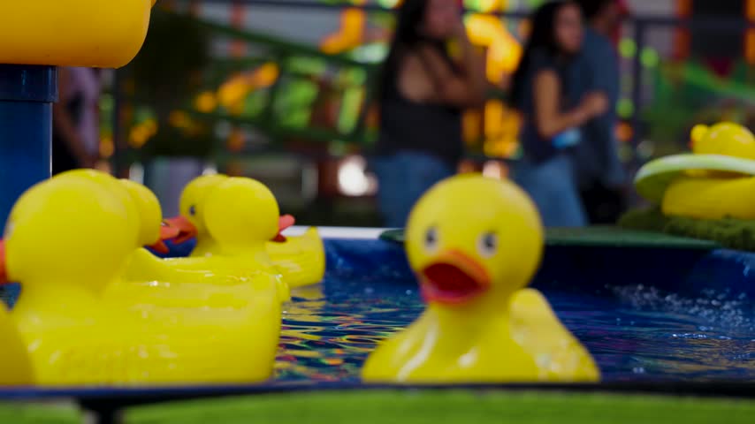 rubber ducks floating in a small pool of water at a carnival.
