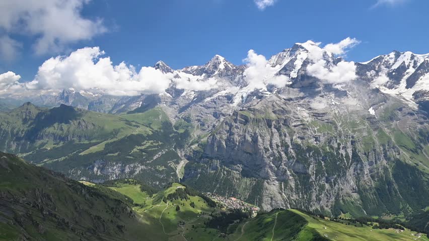 Dramatic alpine panorama of snow-capped peaks, rugged cliffs and green mountain pastures near Birg in the Swiss Alps.