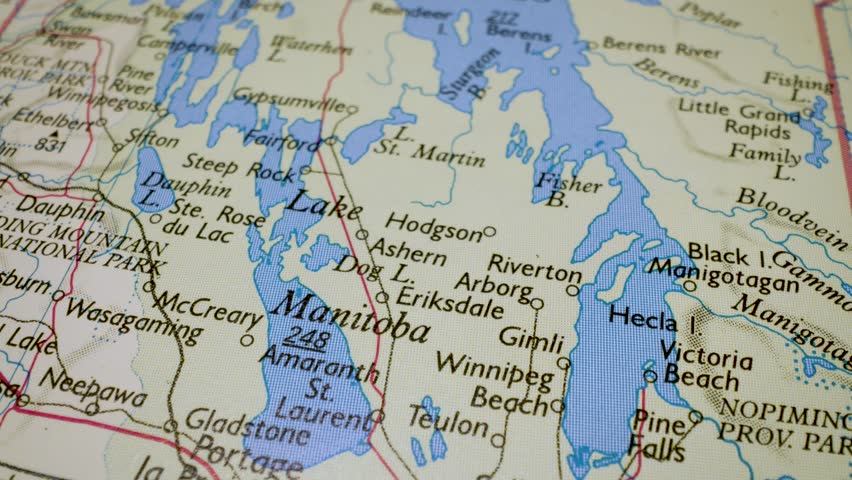Gliding macro view over physical atlas map showing Lake Winnipeg in Canada