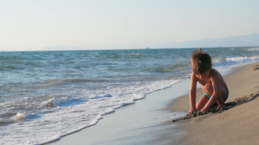 Happy Young Boy Playing in Sand on Sunny Summer Beach