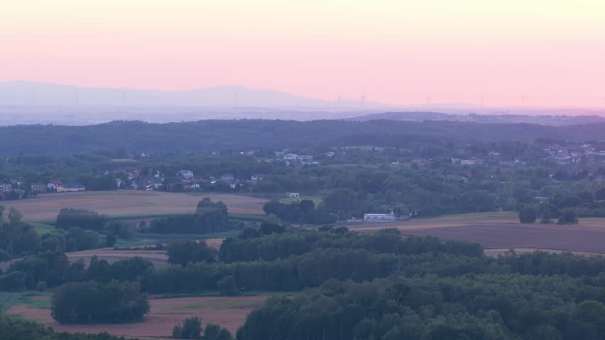 Beautiful pastoral landscape with a hazy mountain range and wind farm on the horizon at dusk
