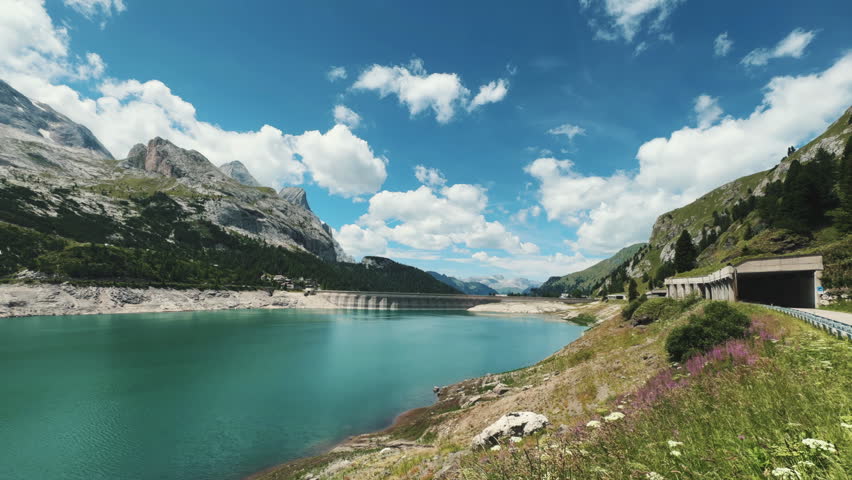 Scenic view of Lake Fedaia reservoir dam and avalanche gallery in Dolomites Alps, Pale Mountains, Italy. Summer alpine turquoise water landscape near Marmolada.