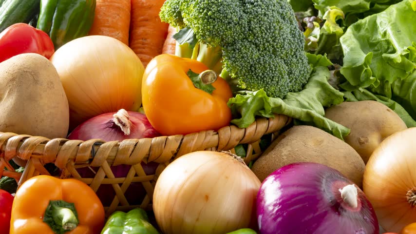 Colorful fresh vegetables including carrots and onions arranged together in a basket
