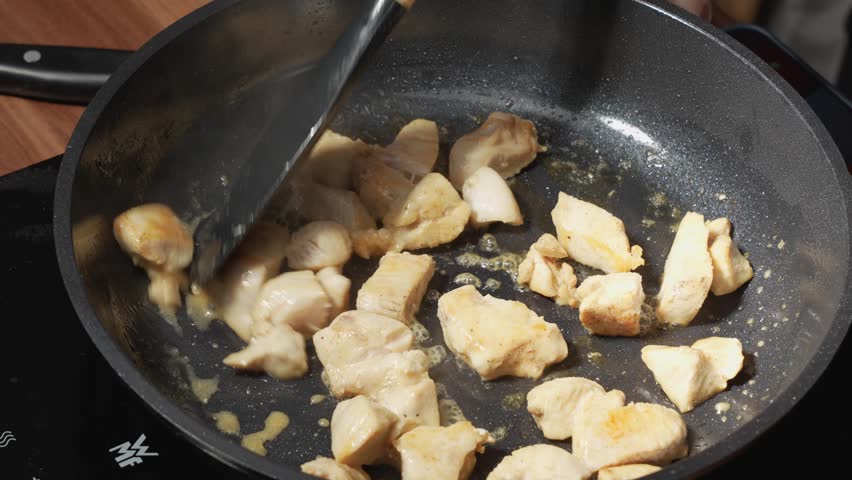 Chicken breast from Gallus gallus domesticus is pan-fried and stirred as it cooks. The pieces begin turning golden for a simple high-protein meal.