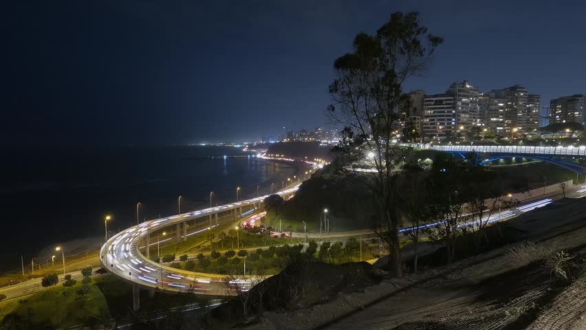 Night-time time-lapse of Armendariz Avenue in Lima, Peru, showing cars driving along the avenue at night. A night view of modern buildings.