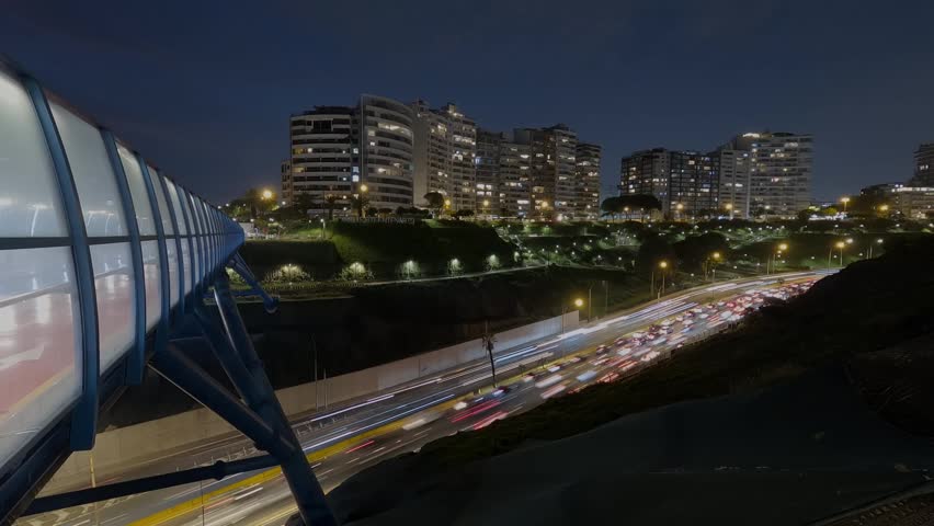 Night-time time-lapse of Armendariz Avenue in Lima, Peru, showing cars driving along the avenue at night. A night view of modern buildings.