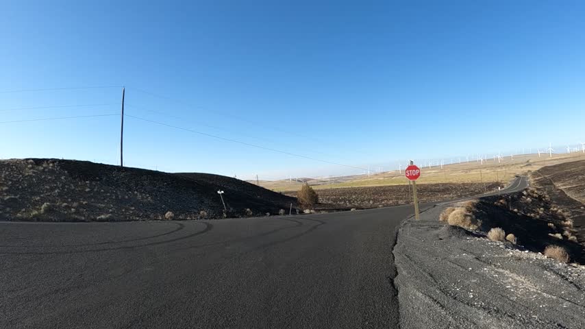 4K action camera footage mounted on a car hood while driving along well paved countryside roads toward Oregon Highway 19 near Arlington, Oregon, USA. The route passes through the rural landscape of north eastern Oregon, with wide open fields, dry rolling terrain, occasional farms, houses and agricultural properties between small towns. Moving driver