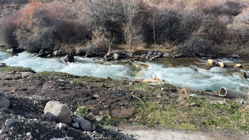 Wide mountain river landscape with flowing water and rocky banks outdoors.