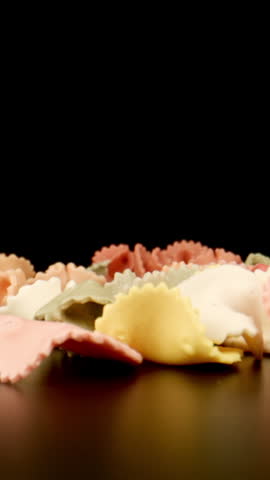 MACRO: Raw colour figural pasta fall on a black table, Slow motion