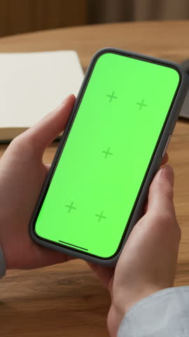 Woman sit use digital tech cell phone, green screen mock up. Hand scroll iphone web site, swipe like photos. Girl hold mobile closeup. Chroma key page. Cozy office background. Online app copy space.