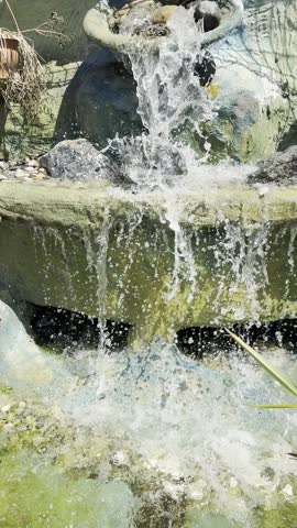 Mini waterfall fountain in the small park on summer day