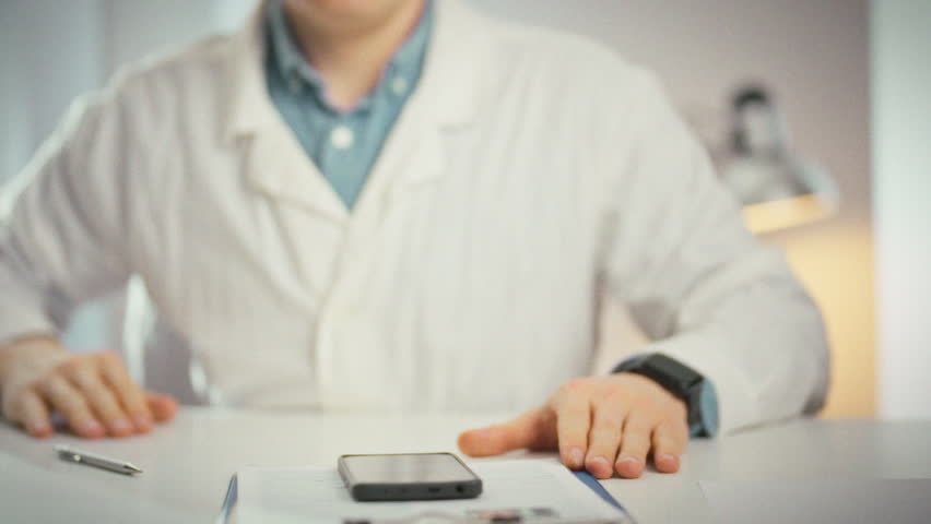 A doctor in a white coat extends a hand, palm outward, signaling stop in a close-up gesture. This universal medicine concept conveys a clear warning or refusal in a clinical office setting
