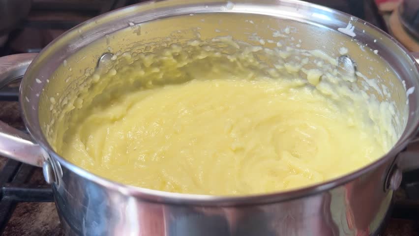 Closeup of creamy mashed potatoes in a steel pot on the stove. Hot homemade puree, cooked potato dish, kitchen cooking, simple comfort meal.