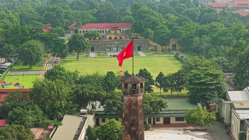 Video of Hanoi Flag Tower flying the Vietnamese national flag, surrounded by lush greenery and historic architecture at the Thang Long Imperial Citadel.