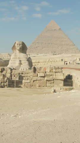 Caucasian female tourist looking and walking towards Great Sphinx with ancient Egyptian pyramids at Giza Plateau in Cairo in background, vertical video