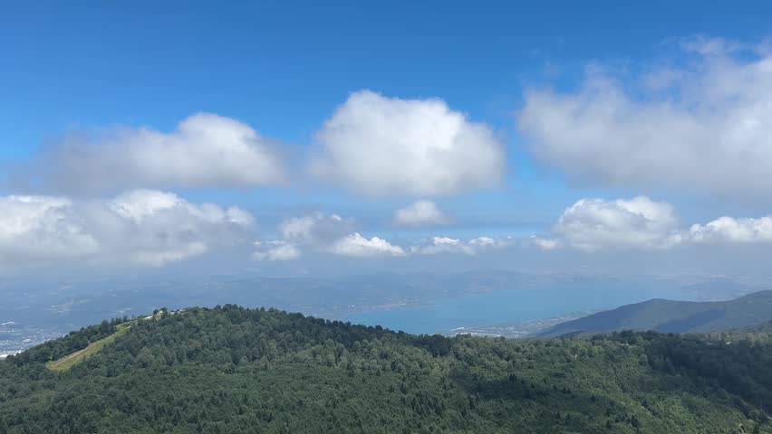 Panoramic View of Sapanca Lake and Forested Mountains Under Summer Clouds captured in a dynamic summer nature scene, showing visible cloud movement across the Kartepe mountain landscape in Turkey.