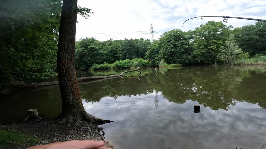 POV of fisherman checking hand and preparing to cast fishing rod with reel at a calm forest lake, outdoor sport angling action.