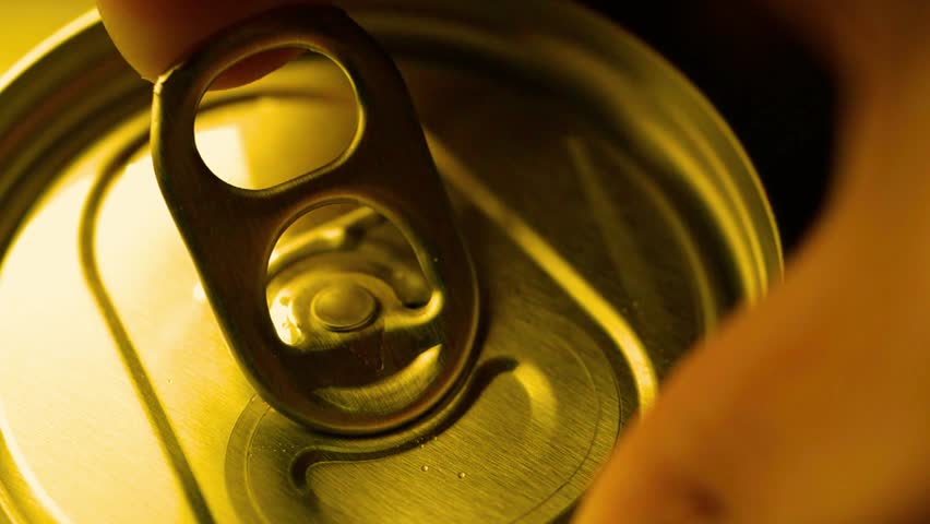 Hand opens cold drink can. Close up of refreshing beverage and metal tab. Slow motion.