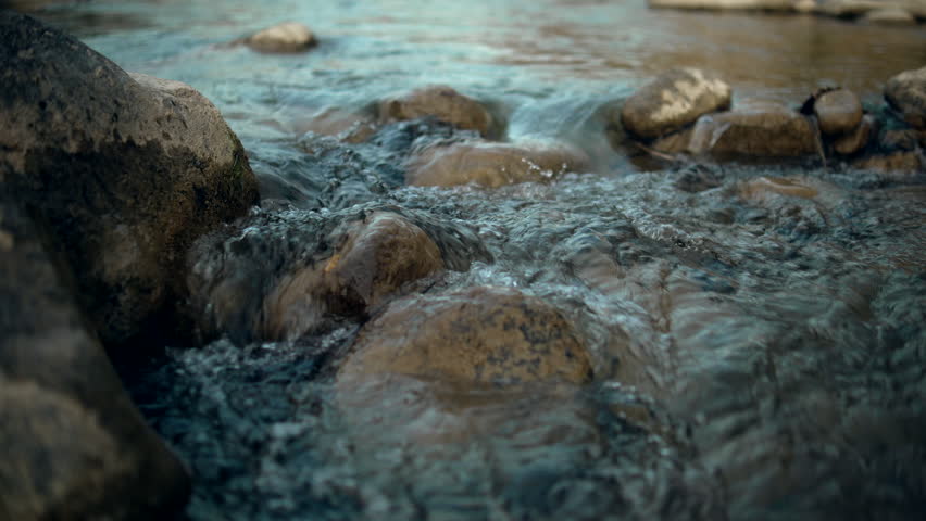 Pristine mountain creek flowing over rocks and stones with crystal-clear spring water, representing natural freshness, wilderness, outdoor adventure, and the serene beauty of untouched nature.