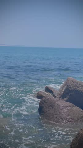 Ocean waves crashing on rocky shore under blue sky