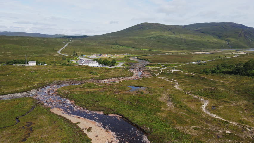 Beautiful aerial of the Slichagan Old Bridge and the new bridge in Isle of Skye, Scotland. Traffic drives over the roads near the landmark and hotel in the Scottish Highlands.