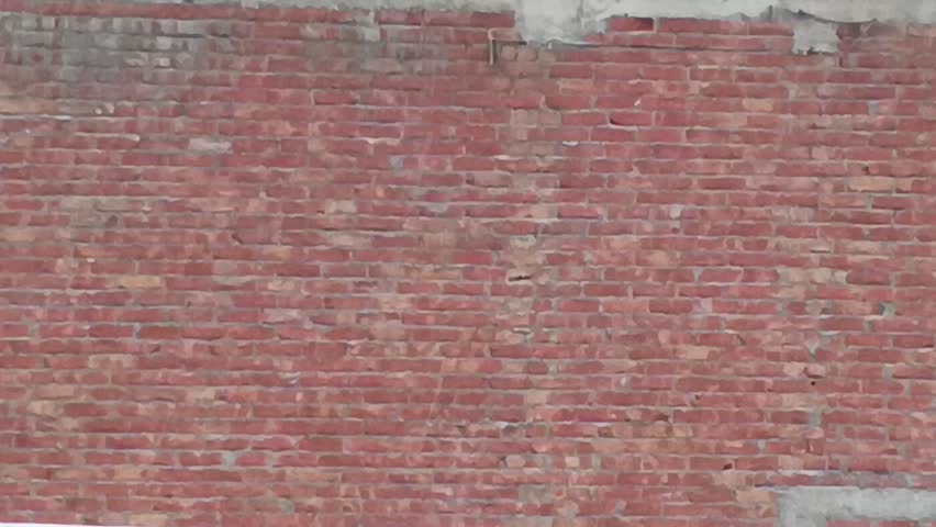 Close-up static shot of a weathered red brick wall.