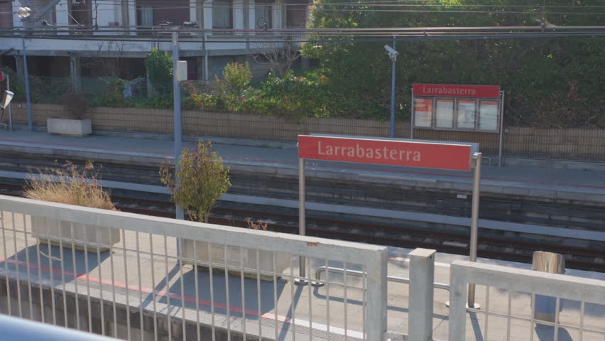 Larrabasterra train station platform with tracks and signs, showing urban public transport infrastructure and travel
