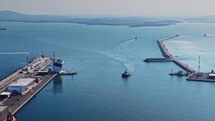 Drone perspective of the maritime terminal, control tower, and tugboats at the entrance of the Port of Burgas during the day.