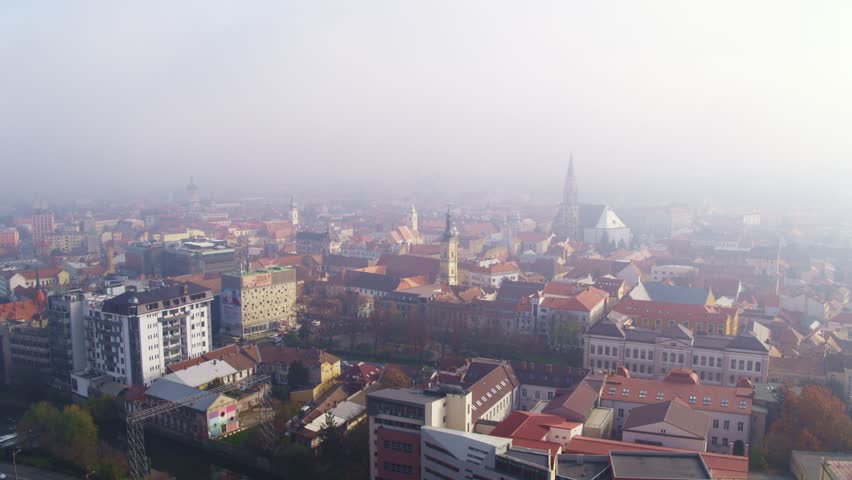 Aerial drone view of downtown Cluj-Napoca city center covered in heavy morning fog