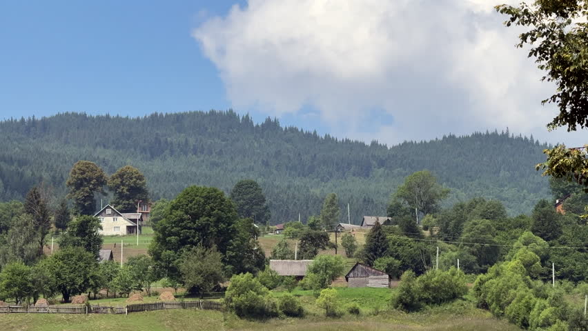 Scenic view of small mountain village with wooden houses nestled under green forest
