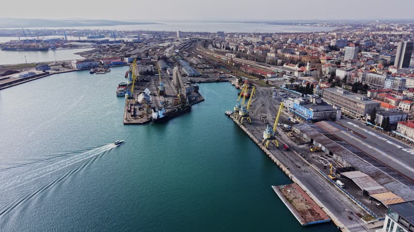 High altitude view showing cargo terminals, port cranes, railway tracks, and the city skyline of Burgas.
