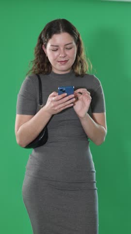 Female person girl scrolls phone screen or types text message, composes response to email. Advertising space, copy space, isolated human figure. Female person on green background, minimalistic