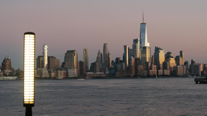 New York City Manhattan Downtown Financial District skyline, World Trade Center tower skyscraper from New Jersey, Hoboken pier, United States. River waterfront urban cityscape, evening dusk twilight.