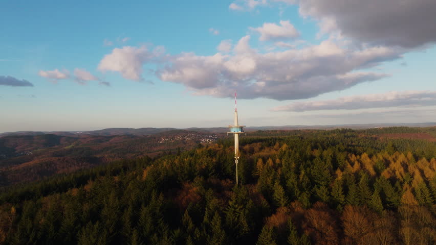 The Melibokus tower stands above autumn forest as clouds gather over the hills