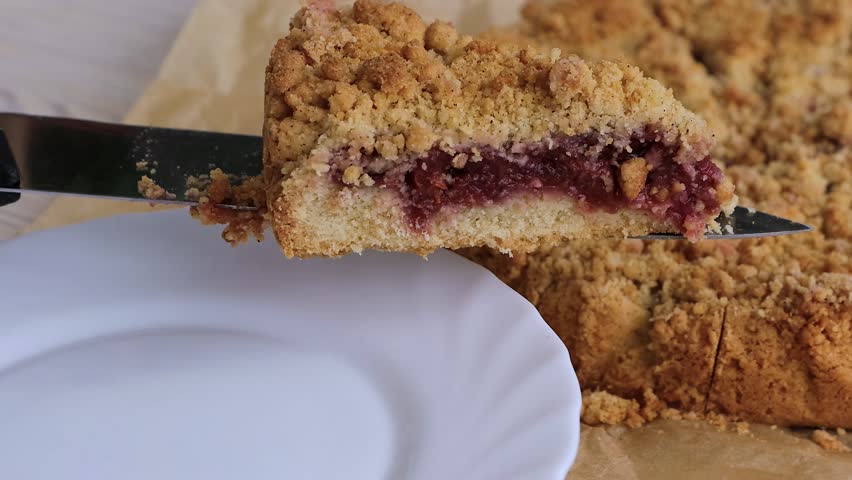 Close-up of a triangular slice of homemade cherry crumb cake resting on a white plate
