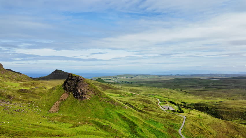 Stunning pan of rocky cliffs and hiking trails on Quiraing mountain in Isle of Skye, Scotland on a sunny summer day