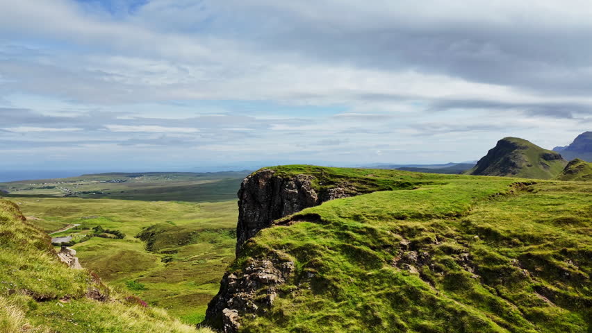 Stunning close up of a rocky cliff at Quiraing mountain overlooking a green valley in Isle of Skye, Scotland on a sunny, summer day