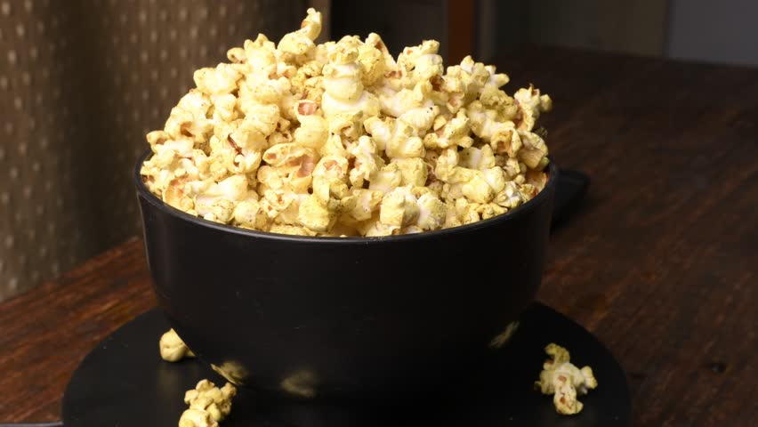 Slow Rotating Popcorn Bowl Showing Crispy Seasoned Kernels on Wooden Surface