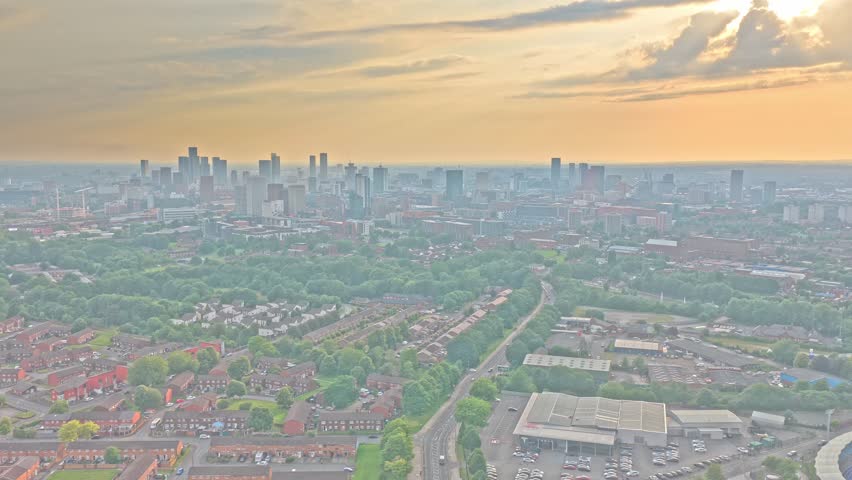 Manchester skyline viewed from East Manchester near Etihad Campus, Manchester, England, United Kingdom, showing the central business district, urban neighborhoods and transport corridors, drone slide.