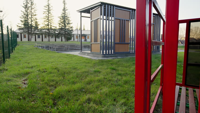 Convenient wooden park pavilion sits near distant amphitheater seating. Peaceful autumn day creates peaceful recreation environment