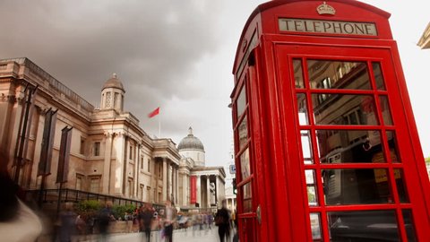 a famous london phone box, with people rushing by, trafalgar square, london
