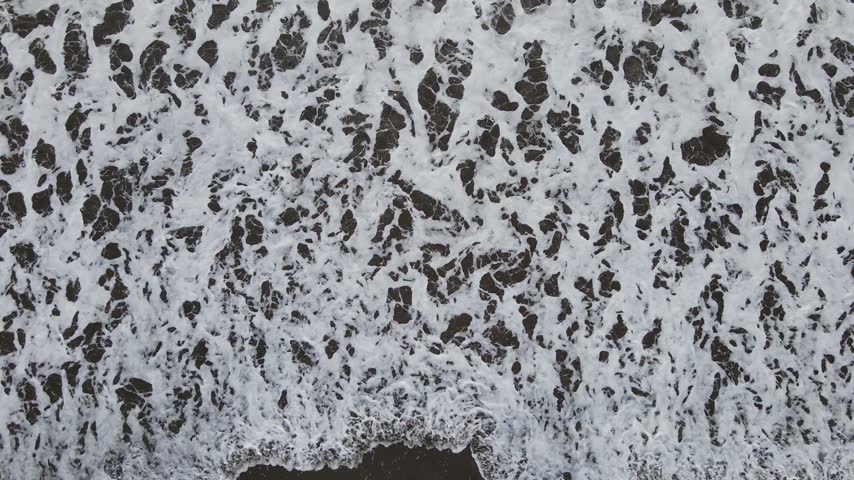 Ocean waves move across muddy sandy shoreline as the drone rises with a downward camera angle, ideal for coastal and natural landscape footage in Southeast Asia