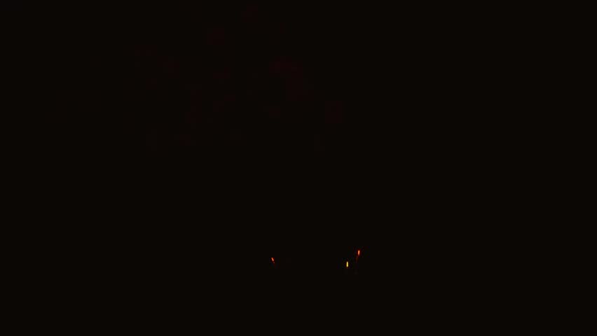 Golden and red fireworks exploding in dark night sky