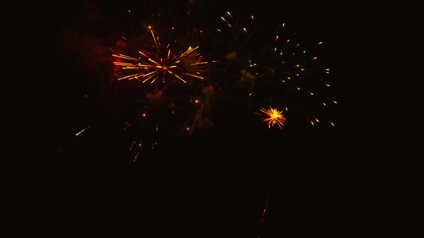 Golden fireworks exploding in dark night sky