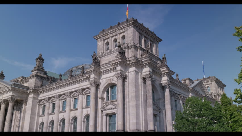 Detailed exterior view of the historic Reichstag building with ornate stone architecture and the German flag in Berlin, Germany.